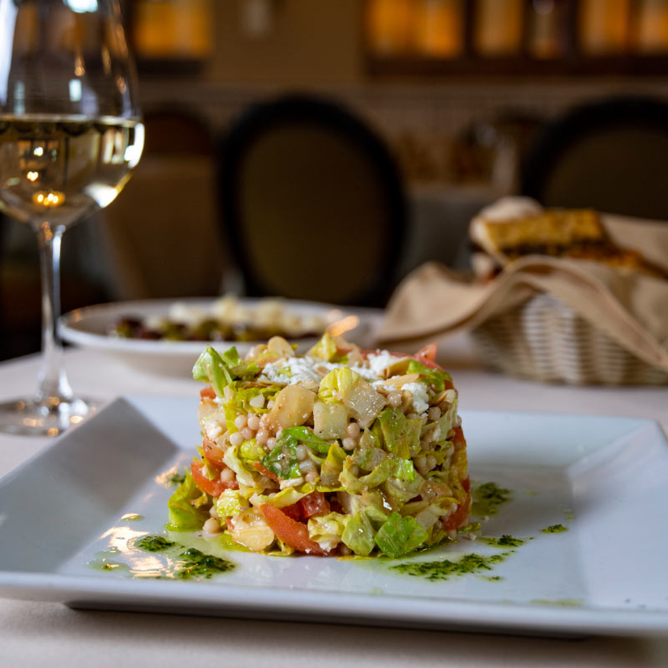 Plated chopped salad with a glass of white wine