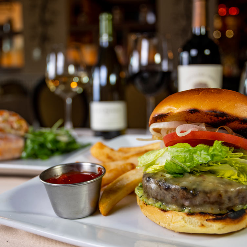 Burger and fries at a table with wine