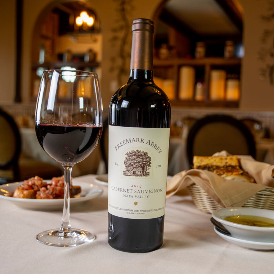 Red wine bottle and glass at a dining table