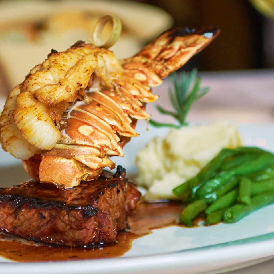 Lobster tail and steak with mashed potatoes and vegetables